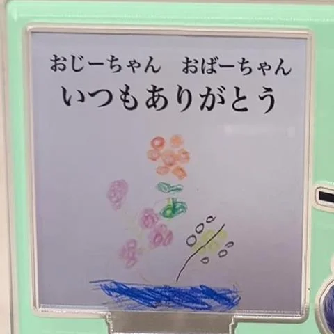 子どもがクレヨンで描いたお花の絵と「おじーちゃん おばーちゃん いつもありがとう」の文字を入れたアクリルプレート